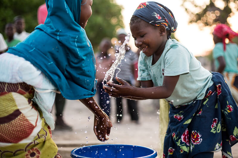 Two children playing with a bucket of water